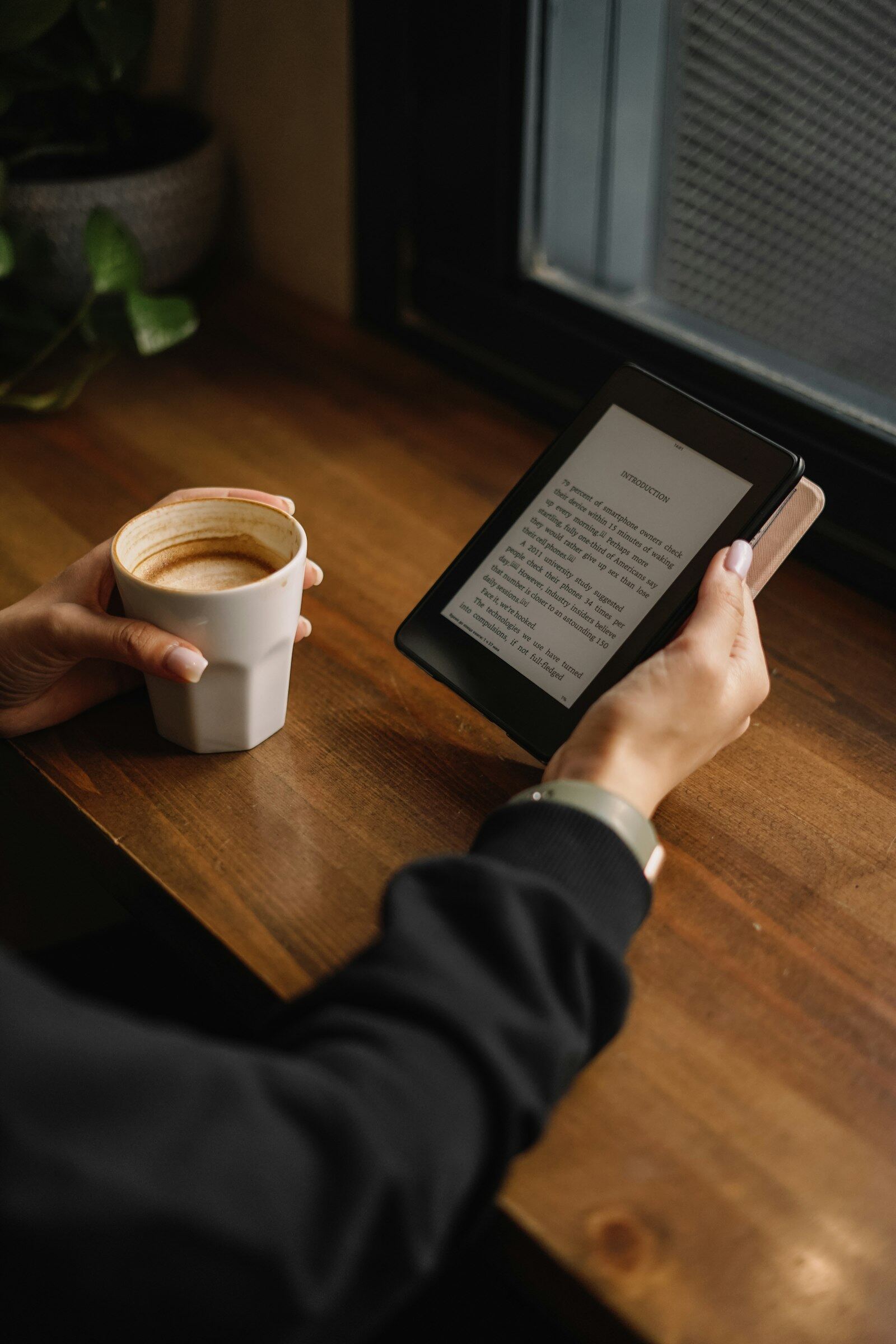 An e-reader resting beside a cup of coffee