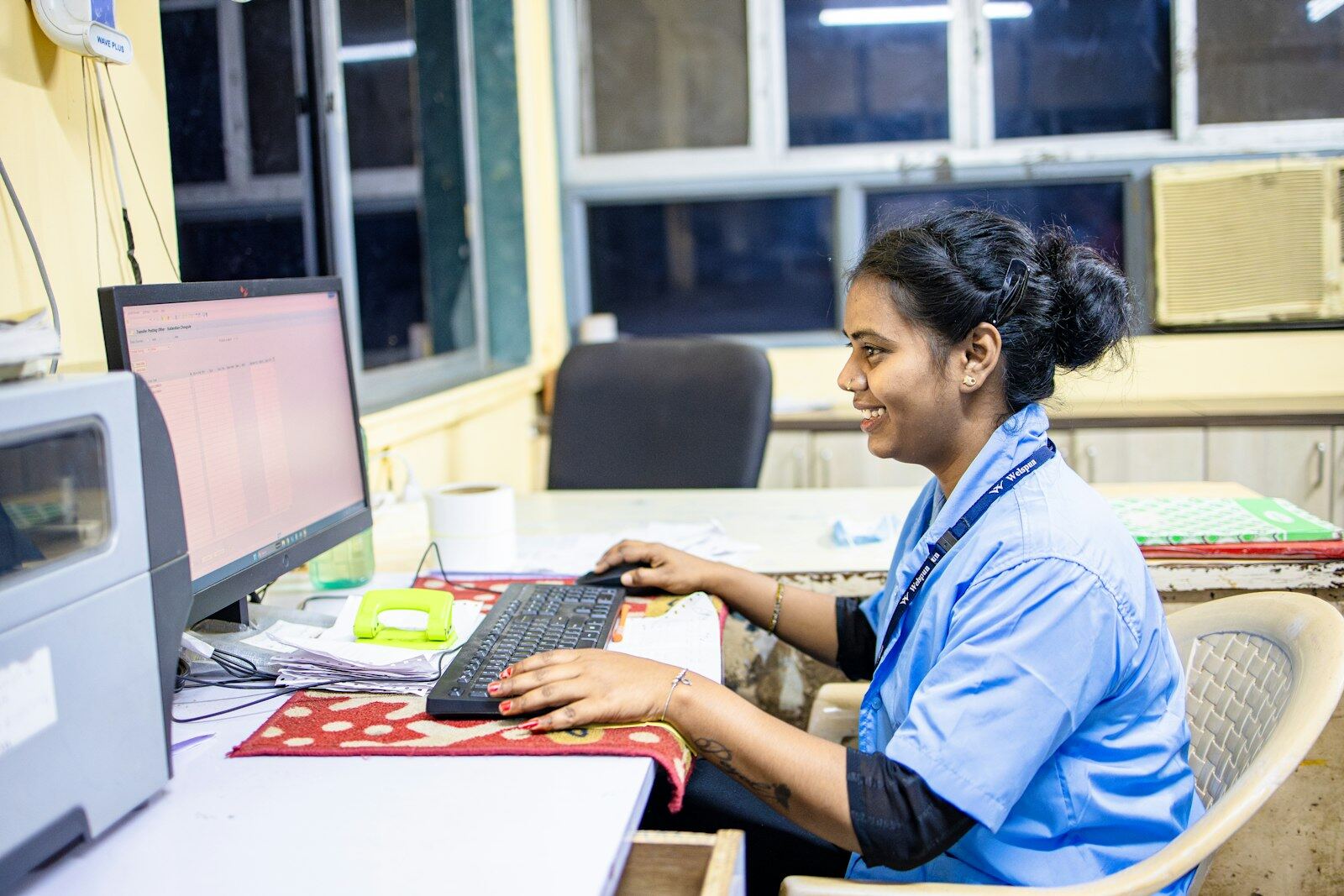 A healthcare administrator smiling while working at a clinic computer