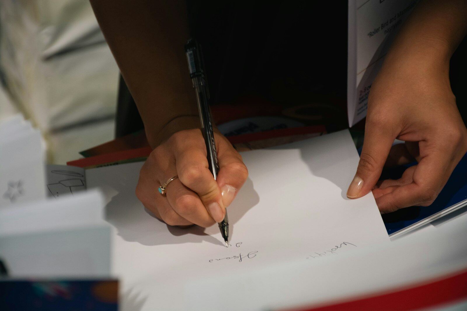 An author signing a copy of a book at a book-signing event, hands only